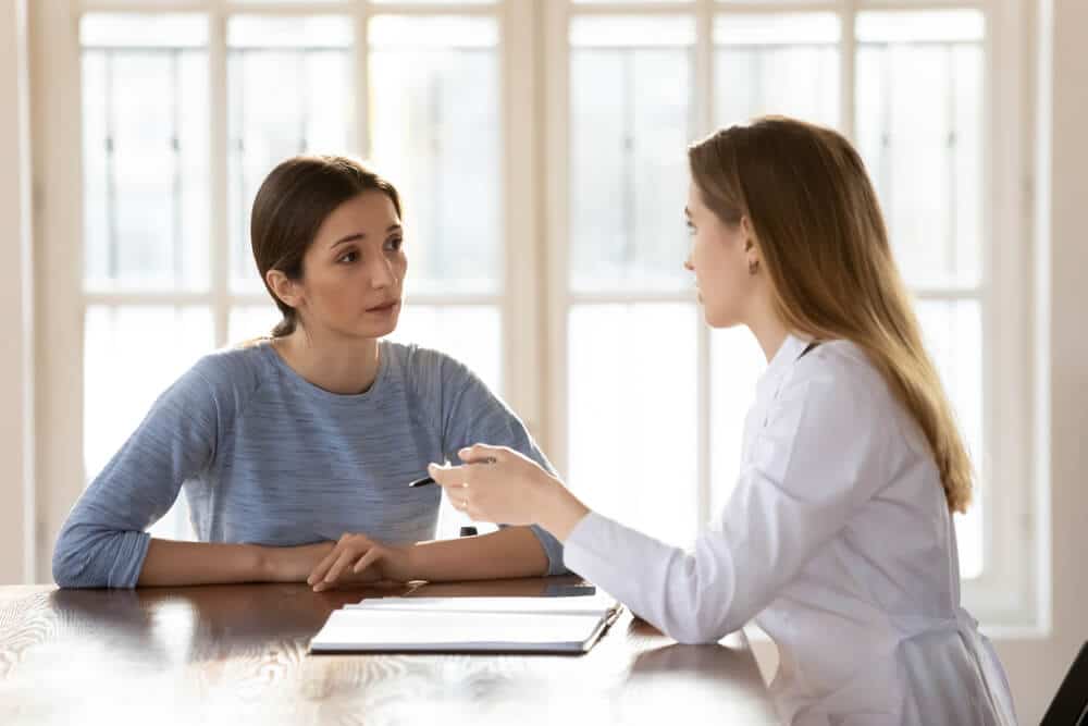 Female Doctor Therapist Wearing White Uniform Consulting Young Woman Patient at Appointment